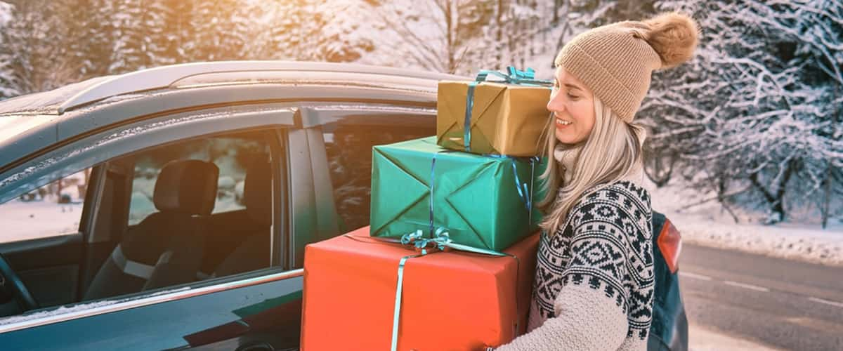 Young woman with christmas gifts loading them into car